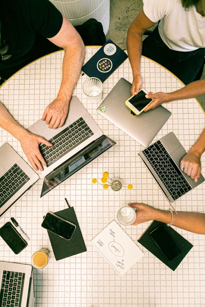 why-choose-us Top view of a team collaborating with laptops, phones, and notes in a modern office.